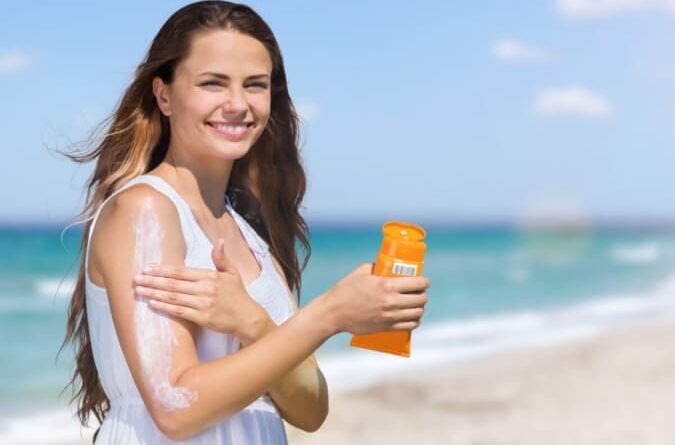 Pessoa aplicando protetor solar durante o verão como forma de prevenção ao câncer de pele